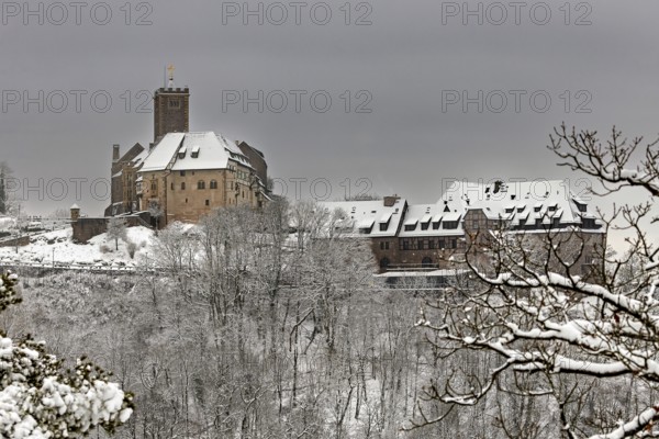 Castle and snowy buildings in a wintry landscape with bare trees, The Wartburg near Eisenach in Thuringia