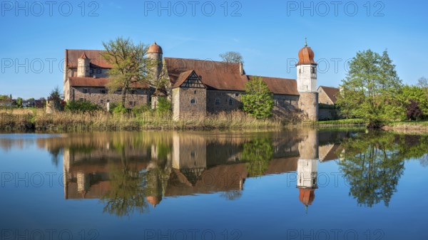 Perfect reflection of Sommersdorf Castle in a pond near Burgoberbach in the Altmühltal, Middle Franconia, Bavaria, Germany