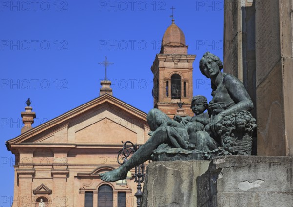 Monument with a statue in Piazza Unita and the Santo Stefano Collegiate Church in the city of Novellara, Emilia-Romagna, Italy