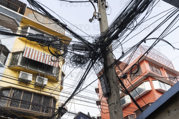Bangkok, Thailand. March 4th 2025. A tangled mess of cables and wires used for phone and internet connections hanging from a pole in the street in central Bangkok, Thailand