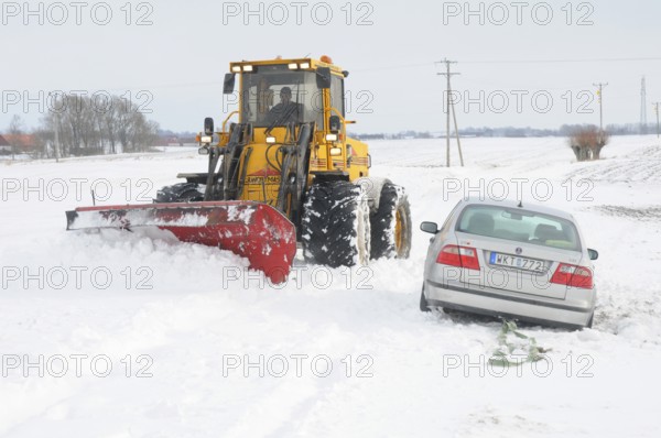 Car stuck in snow gets help from a loader to get free in Skurup municipality, Skåne county, Sweden, Scandinavia