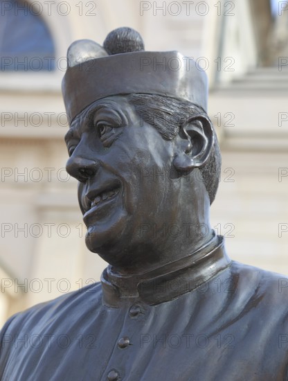 Italy, in the village of Brescello, statue of Don Camillo, portrayed by actor Fernand Joseph Desire Contandin, known as Fernandel, in front of the church of Santa Maria Nacente e San Genesio, Emilia Romagna, Italy
