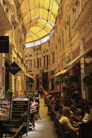 Romania, capital Bucharest, Bucuresti, restaurants and cafes in Passage Macca-Villacrosse, Pasajul Macca-Vilacrosse, an arcade street covered with yellow glass in the center of the city