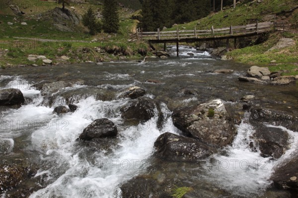 Torrent and old wooden bridge on the Transfogarasan High Road, Transfagarasan, connects the Arges Valley in Great Wallachia with the Olt Valley in Transylvania, crossing the Fagaras Mountains in the Transylvania Alps, to melt snow in May, Romania