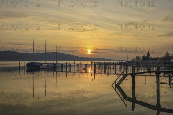 Atmospheric sunrise scene with calm water and sailboats on the jetty, Lake Constance, Überlinger See, Bodman-Ludwigshafen, Konstanz district, Baden-Württemberg, Germany