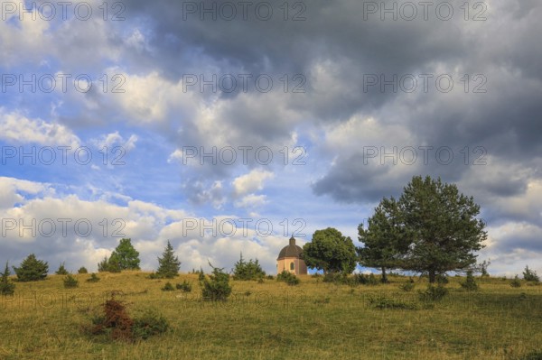 A small chapel stands on a green hill under a cloudy sky with trees, Upper Danube nature park Park, Josefskapelle, Alter Berg Landscape Protection Area, Böttingen, Großer Heuberg, Tuttlingen District, Baden-Württemberg, Germany