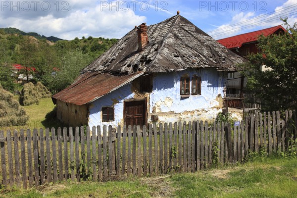 Traditional Romanian farmhouse that is in a dilapidated or abandoned state. The eye-catching light blue color of the outer walls is common in many Romanian villages, such houses are characteristic of rural regions in Romania, particularly Transylvania, Transylvania