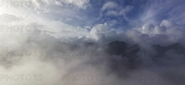 Atmospheric scene with clouds and fog over a mountain landscape under blue sky, hiking in the High Tatras National Park, Carpathian Mountains, Poland
