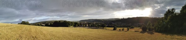 Panoramic landscape at dusk with a wide field and a cloudy sky, Kronach, Frankenwald nature park Park
