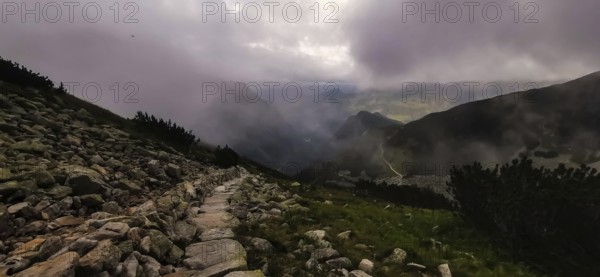 A lonely stone path in a foggy mountain landscape at dusk, hiking in the High Tatras National Park, Carpathian Mountains, Poland