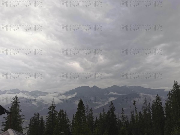 View of a mountainous landscape with clouds and conifers wrapped in fog, Zakopane, hiking in the High Tatras National Park, Carpathian Mountains, Poland