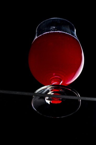 A cognac glass with red liquid, dramatically illuminated, view from below