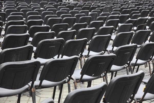 Chairs covered with gray plastic stand in rows in a function room, empty, vacant, seating