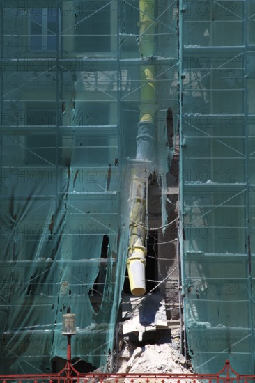 Construction site, house with scaffolding and a net in front of it as dust protection, waste tunnel for construction waste, renovation, renovation