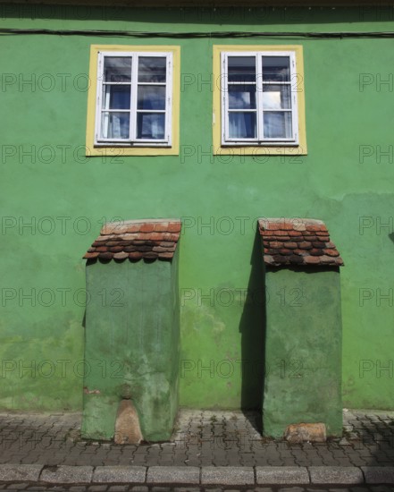 Green house façade with two small windows in the old town of Sighisoara, German Sighisoara, town in Mures district in Transylvania, Romania