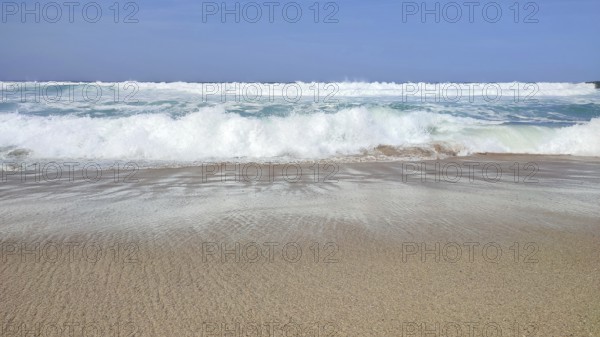 Empty sandy beach with breaking waves under clear blue skies, hiking on the Fisherman's Trail, Southwest Alentejo nature park Park and Costa Vicentina, Portugal