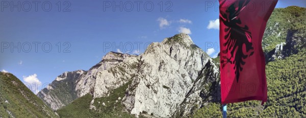 Mountain landscape with the Albanian flag against a clear sky and impressive rock formations, Peaks of the Balkans, hiking in the Albanian Alps National Park, Albania