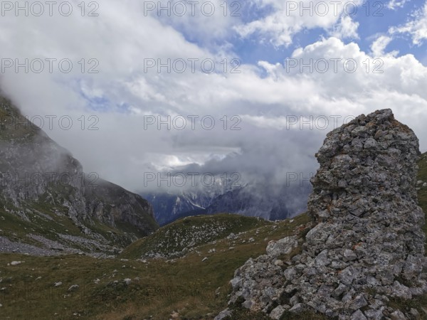Dramatic mountain scene with fog covered peaks and lonely rock structure, Peaks of the Balkans, hiking in the Albanian Alps National Park, Albania