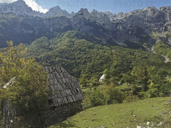 Dilapidated wooden house in a green mountain landscape under a blue sky, Peaks of the Balkans, hiking in the Albanian Alps National Park, Albania