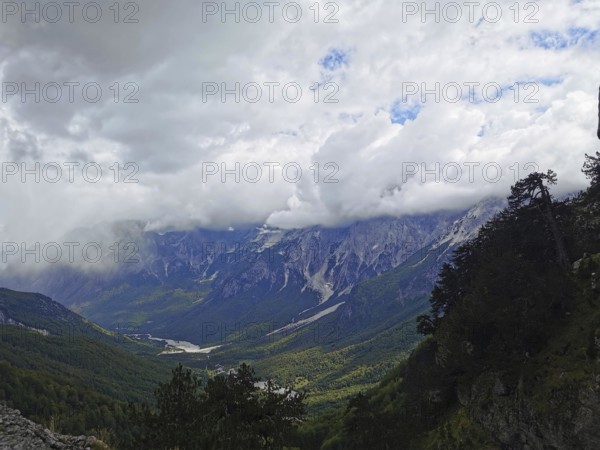 Dramatic cloud cover over a wide valley and towering mountains, Peaks of the Balkans, hiking in the Albanian Alps National Park, Albania