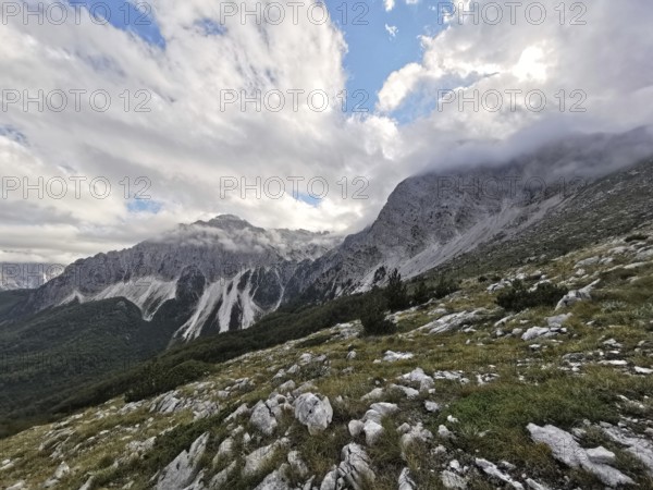 View of a mountainous landscape with dramatic clouds and rocks in the foreground, Peaks of the Balkans, hiking in the Albanian Alps National Park, Albania