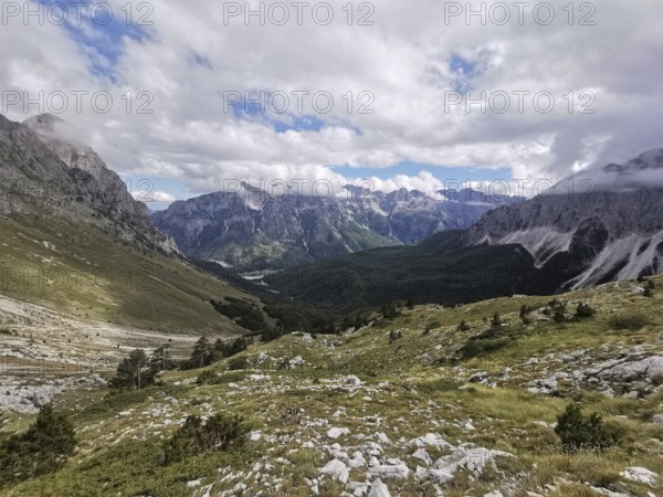 View of magnificent mountain landscape with a winding valley and clouds, Peaks of the Balkans, hiking in the Albanian Alps National Park, Albania