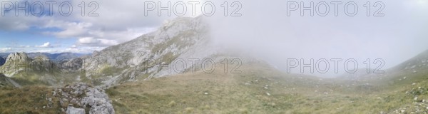 Mountain landscape with fog that partially obscures the view, under a changing sky, Peaks of the Balkans, hiking in the Albanian Alps National Park, Albania