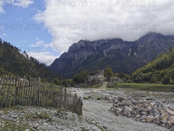 Rocky area and fences lead to a small village in an alpine environment, Peaks of the Balkans, hiking in the Albanian Alps National Park, Albania