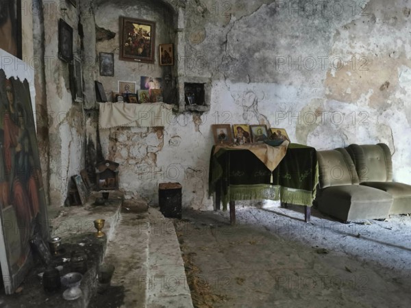 Atmospheric interior view of an abandoned Orthodox chapel with icons and dilapidated walls, Himare, Albania