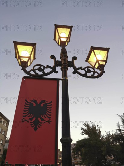 Elegant street lamp with Albanian flag at dusk in the city with cozy light, Albania