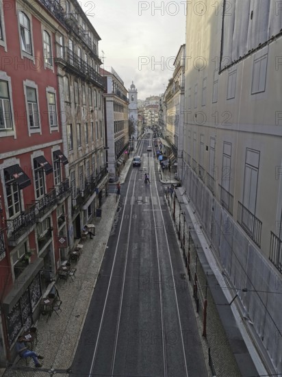 View from above of a long, empty city street with tram tracks, Lisbon, Portugal