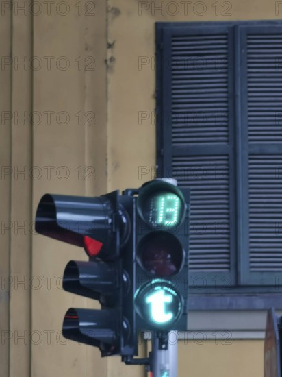 Close-up of a green traffic light in Tirana green letter T in front of a building with shutters closed, Tirana, Albania