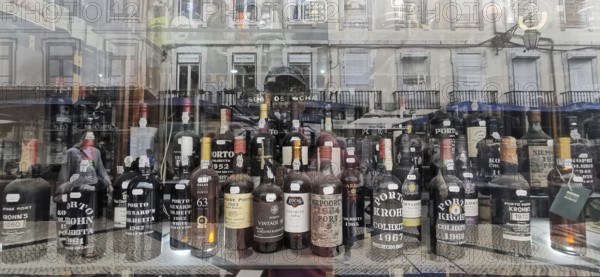 Old port wine, wine bottles and spirits in a shop window with city reflections in the background, Lisbon, Portugal