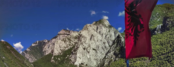 Alpine landscape with an Albanian flag and majestic mountains under blue sky, Peaks of the Balkans, hiking in the Albanian Alps National Park, Albania