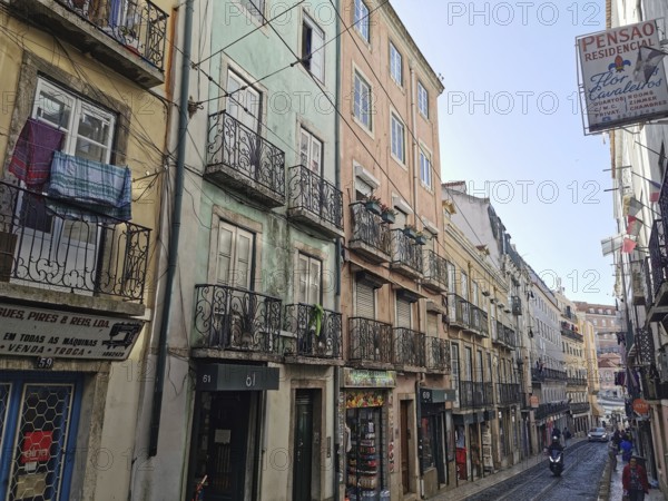 View of a street with colorful buildings, laundry hanging on wrought iron balconies in Lisbon, Old Town, Lisbon, Portugal
