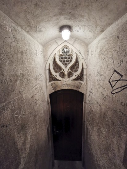 Stone staircase in an old building leading to a decorated door with graffiti on the walls, Ulm