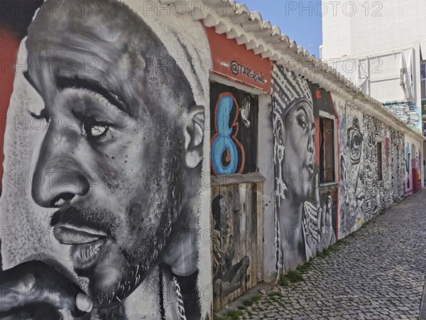 Wall with large-format graffiti in black and white of several expressive faces, Lagos, Algarve, Portugal