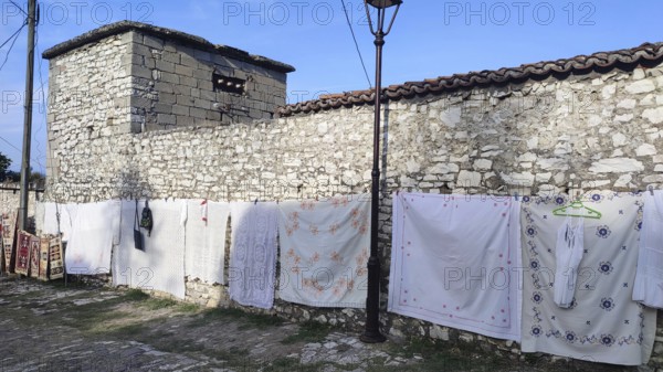 Bed sheets and towels dry on a line in front of an old stone wall, Berat, Albania