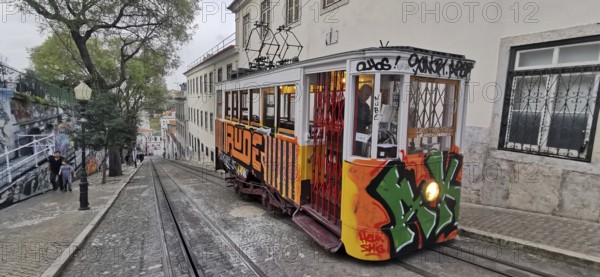 Historic funicular, Elevador da Gloria with graffiti goes down a steep road, Lisbon, Portugal