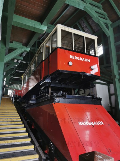A red mountain railway is located in a covered area surrounded by green wooden structures, Oberweissbach cable car, Rennsteig, Thuringian Forest nature park Park