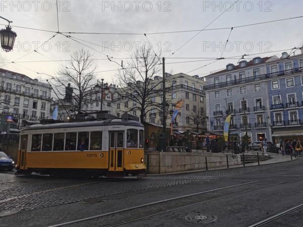 A yellow, historic tram stands in the city center at dusk, Lisbon, Portugal