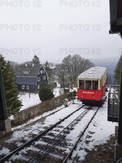 Red train goes through snow-covered mountain landscape, Oberweissbach cable car, Rennsteig, Thuringian Forest nature park Park