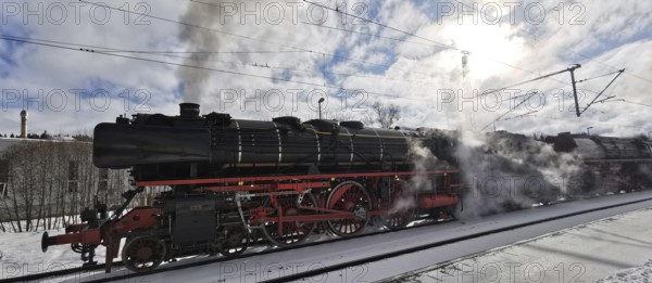 A historic steam locomotive emits smoke while standing on tracks in winter, Rennsteig, Frankenwald nature park Park
