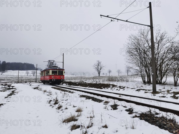 A red train travels through a snow-covered landscape, snow-covered fields in the background, Oberweissbach cable car, Rennsteig, Thuringian Forest nature park Park