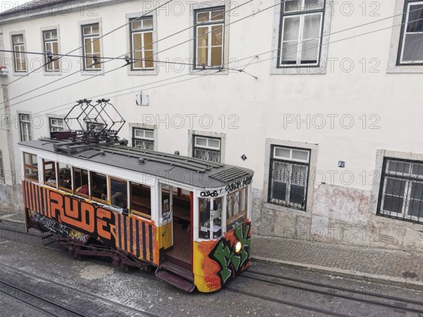 Historic funicular, Elevador da Gloria with colorful graffiti goes down a steep road, Lisbon, Portugal