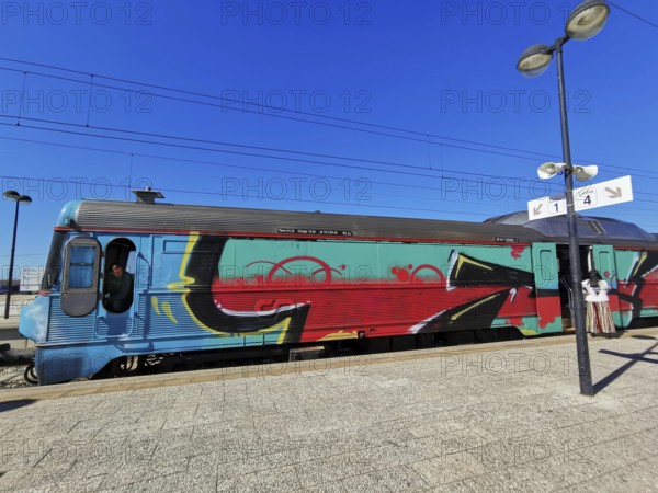 A train painted with graffiti stands on a sunny platform, Lagos, Algarve, Portugal