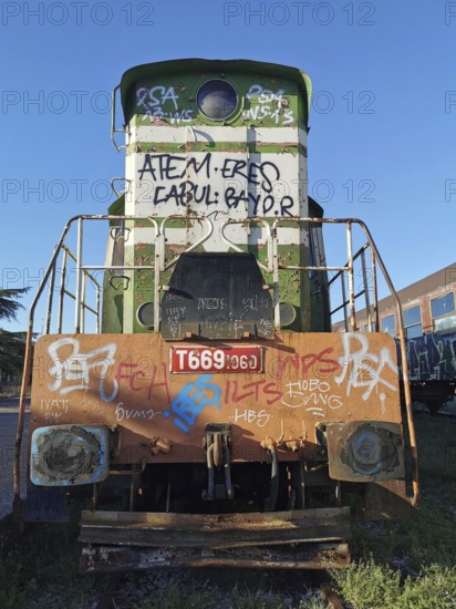 Front of a green locomotive with graffiti in daylight, Albania
