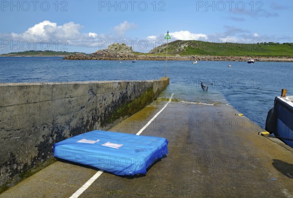 Small pier leading into the sea, colorful sky with clouds, boats and rocks in the background, St Agnes, Isles of Scilly, Cornwall, Great Britain