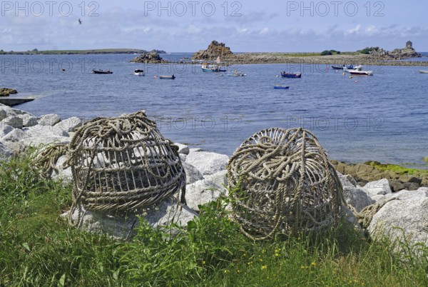 Large rope rolls lie on the shore with a wide view of the sea and several boats, lobster cages, St Agnes, Isles of Scilly, Cornwall, Great Britain