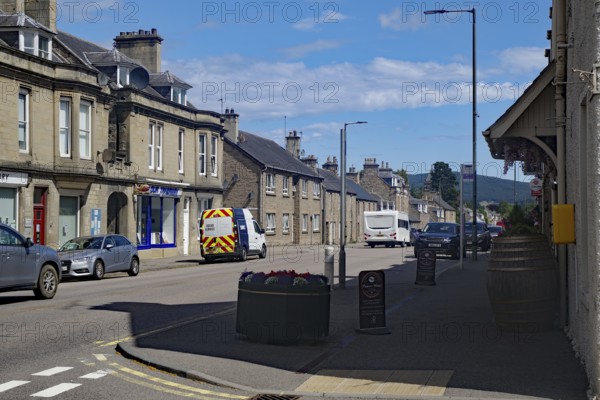 Urban street scene with cars and buildings under blue sky, Dufftown, Aberdeenshire, Scotland, United Kingdom